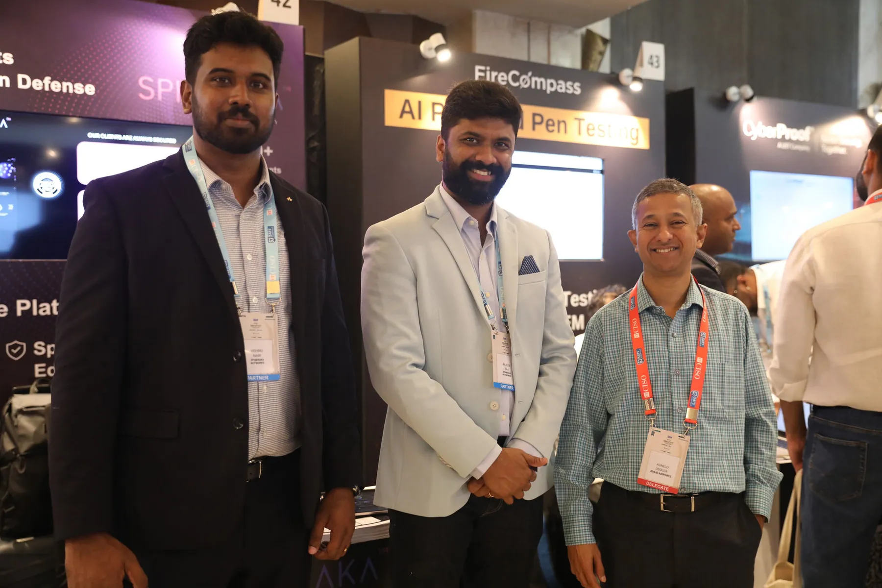 Two members of the Spharaka team with a summit delegate in front of the Spharaka exhibition stand.