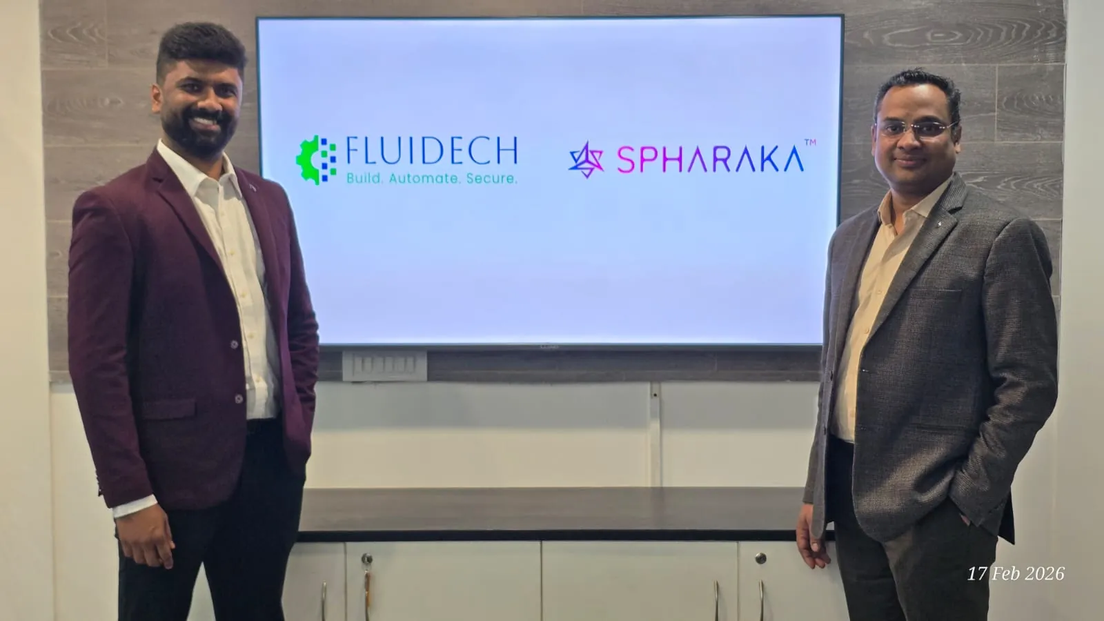 Two representatives standing either side of a screen carrying the Fluidech and Spharaka logos, marking the announcement of their autonomous SOC partnership.